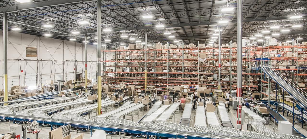 Wide view of a distribution center floor with conveyor lanes and pallet racking